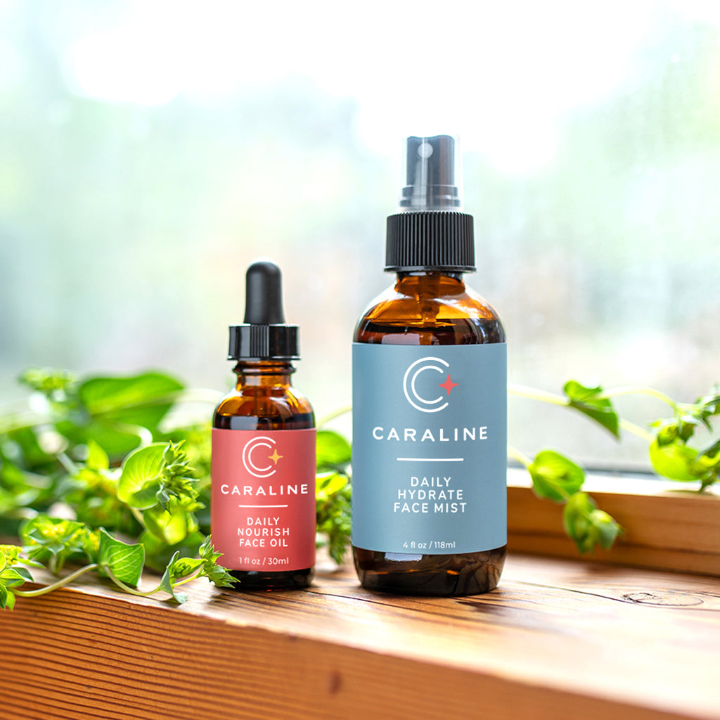 lt text Caraline Skincare Daily Nourish Face Oil and Daily Hydrate Face Mist in bottles in front of a window