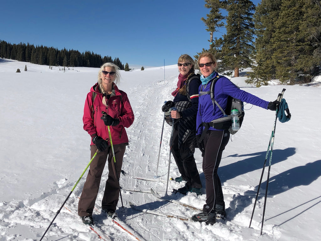 Three older women cross-country skiing in Colorado on a sunny day