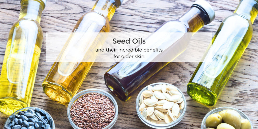 Bowls of seeds and bottles of plant oil on a wood background